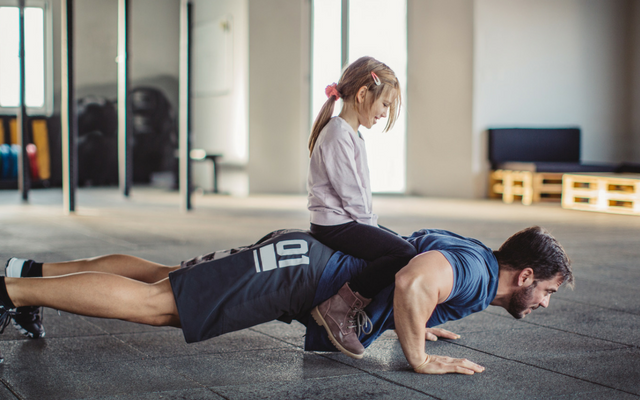 Child sitting on person's back while they do a push-up