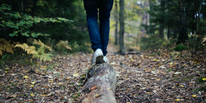 Close up image of person walking on a log in the woods