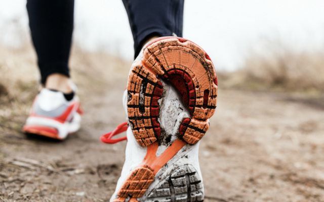 Close up image of running shoes on a muddy trail