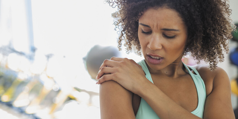 Person with pained look holding their shoulder